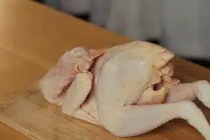 Whole raw Aurum Cockerel on a wooden chopping board