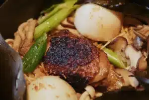 Kombu-cooked rice in cast iron with crisp chicken thigh, duck egg, mushrooms and spring onion