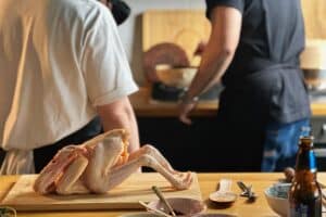 Whole Aurum Cockerel on a chopping board with chefs cooking in the background